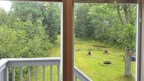 A view from a room with a window overlooking a grassy area with trees. A sign above the window reads "GREAT SACANDAGALAKE."