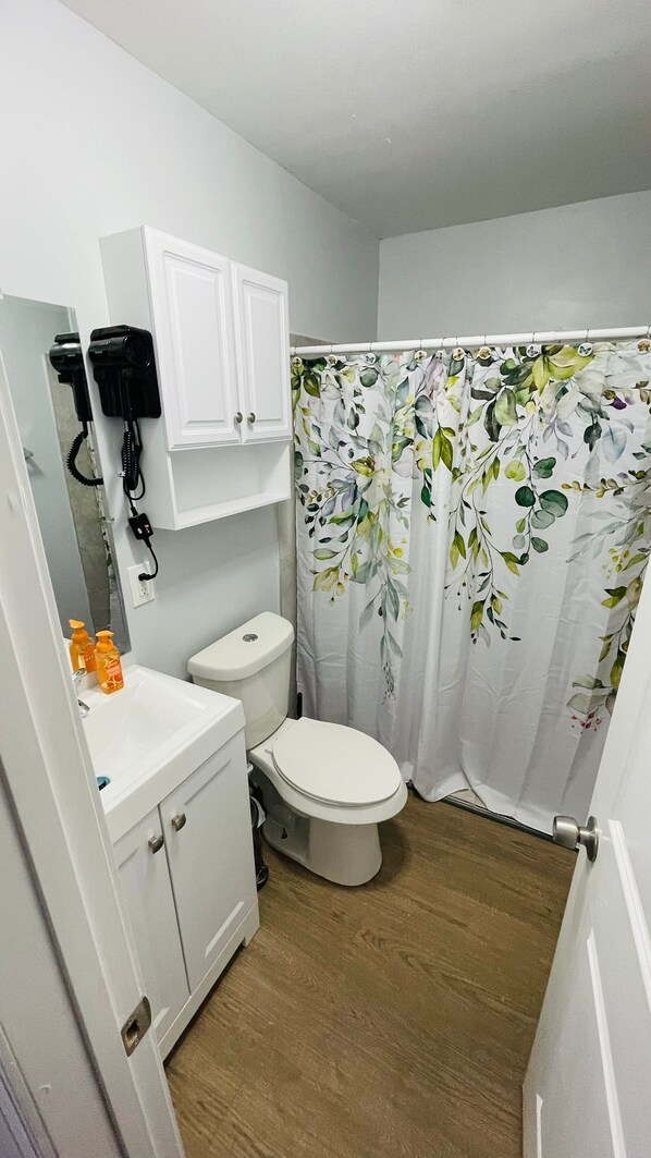 A small bathroom with a toilet, a sink, a cabinet, and a shower curtain with a floral pattern.