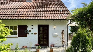 A house with a tiled roof, a front door, and a small garden with potted plants. - Seepanorama by Interhome (Öhningen)