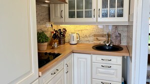 A kitchen with white cabinets, a wooden countertop, a stove, and a sink. - Seepanorama by Interhome (Öhningen)