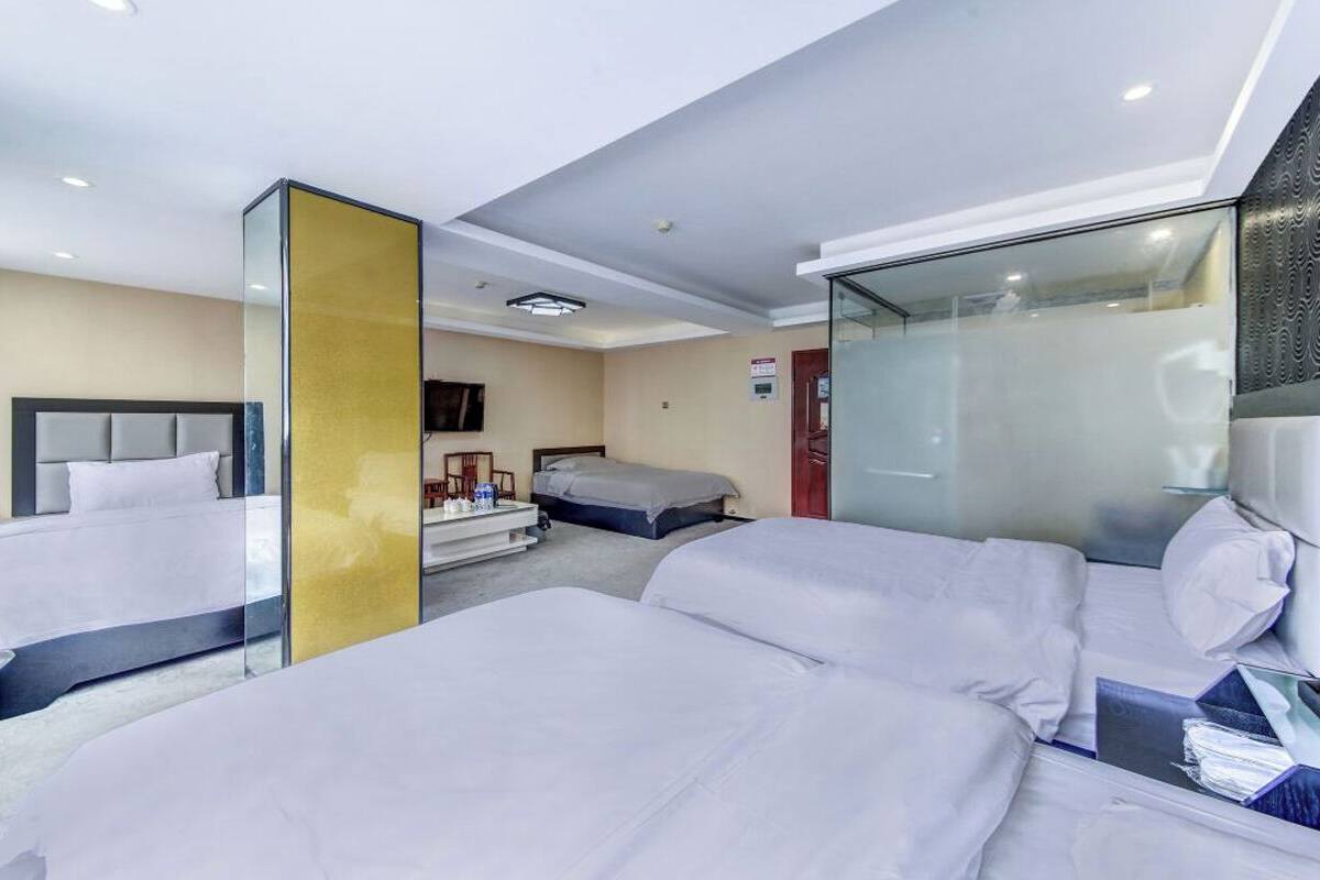 Ein Hotelzimmer mit zwei Betten, einem Schreibtisch, einem Stuhl und einer Glastrennwand.