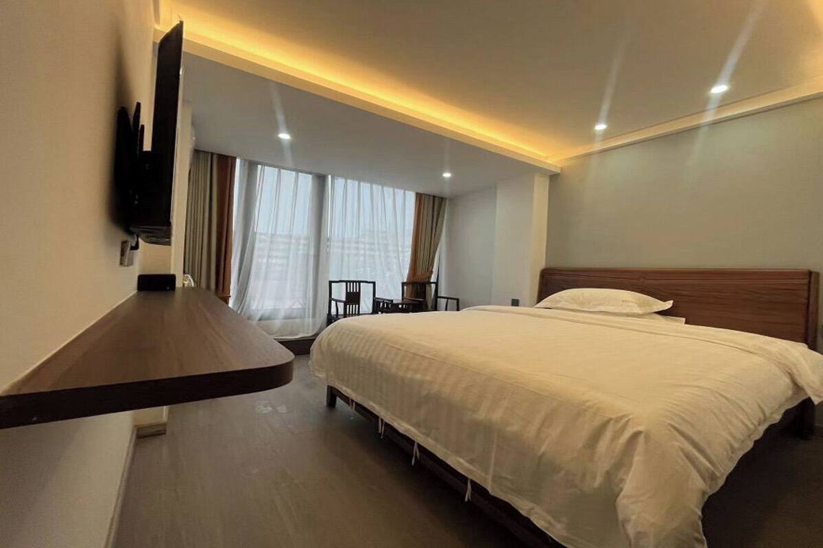 Ein Hotelzimmer mit Bett, Wandfernseher, Schreibtisch und Stuhl.