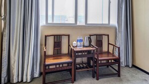 A room with two wooden chairs, a small table, and a window with curtains. - StarChain Zengcuoan Hotel Xiamen (Xiamen)