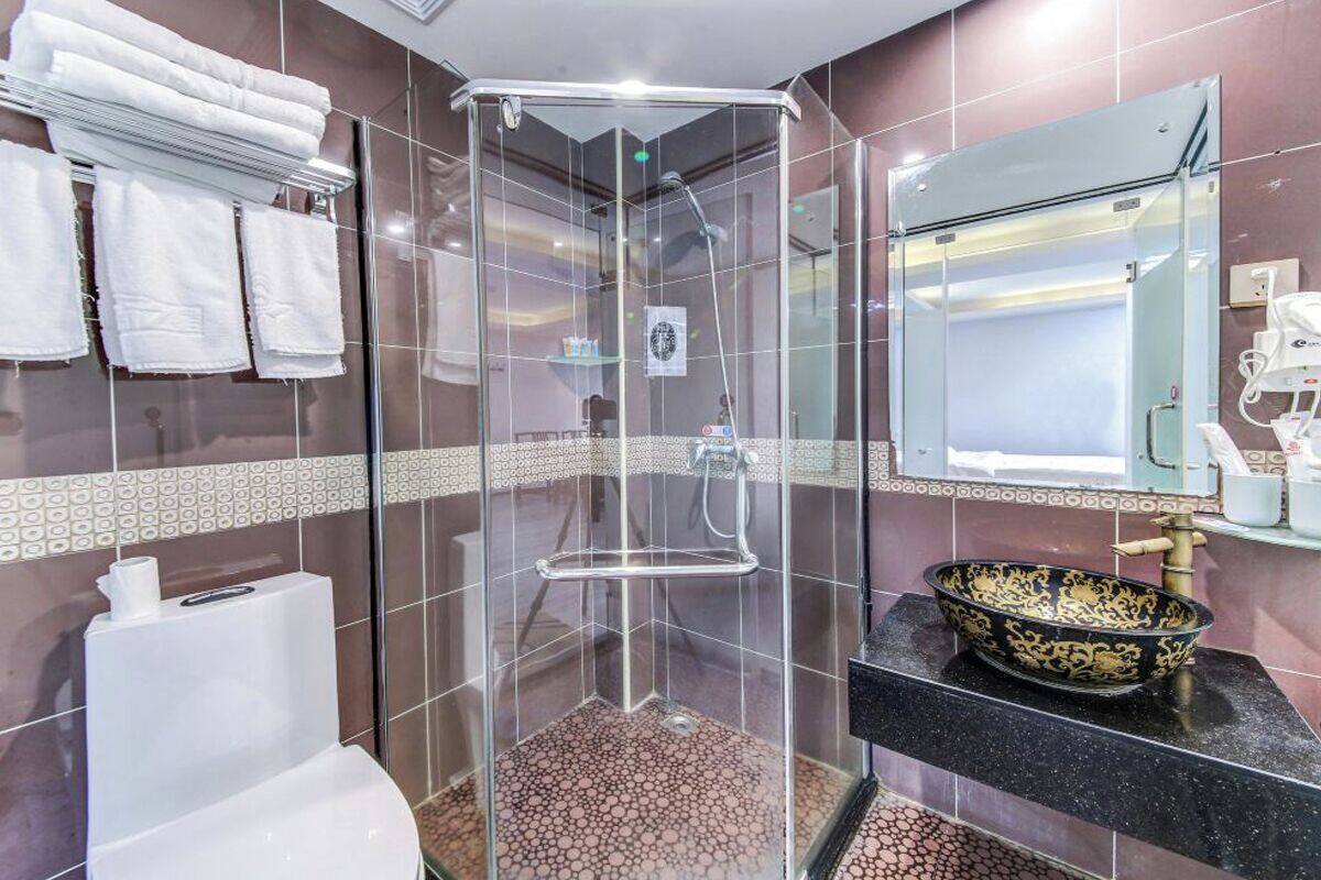 Ein modernes Badezimmer mit einer gläsernen Duschkabine, einer schwarzen Ablage mit einem dekorativen Topfbecken und einem Spiegel über dem Waschbecken.