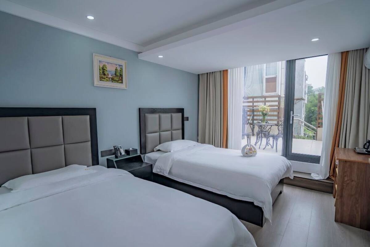 Ein Hotelzimmer mit zwei Betten, einem kleinen Tisch, einem Stuhl und einem Balkon mit Aussicht.