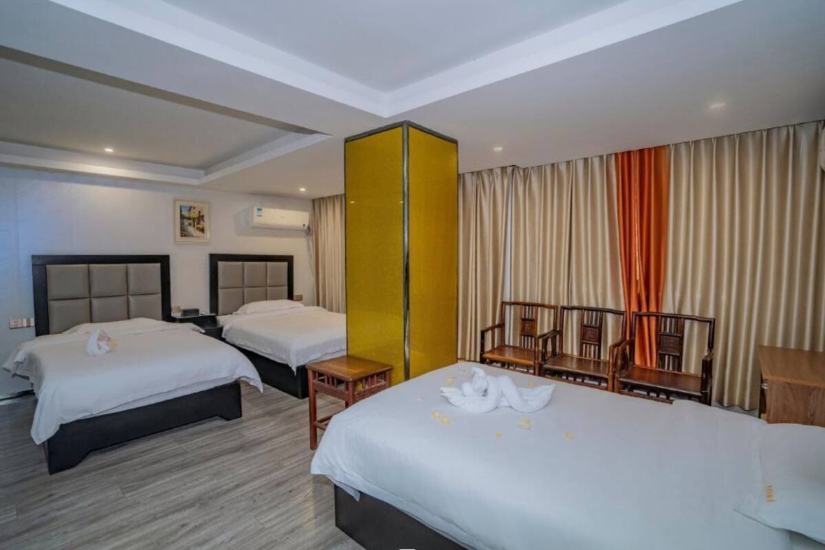 Ein Hotelzimmer mit zwei Betten, einer hölzernen Bank und einer gelben Trennwand.