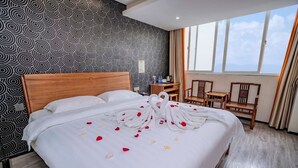 A hotel room with a large bed, a wooden headboard, a desk with a chair, and a view of the sky through large windows. - StarChain Zengcuoan Hotel Xiamen (Xiamen)