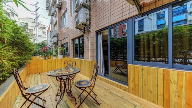 A wooden deck with a round table and chairs, surrounded by a wooden fence and greenery. - StarChain Zengcuoan Hotel Xiamen (Xiamen)