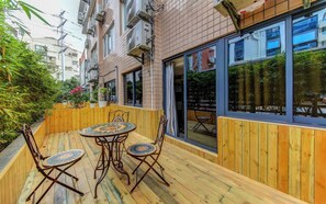 A wooden deck with a round table and chairs, surrounded by a wooden fence and greenery. - StarChain Zengcuoan Hotel Xiamen (Xiamen)