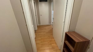 A narrow hallway with wooden flooring and white walls.