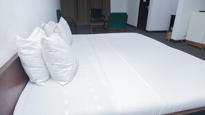 Ein Hotelzimmer mit einem großen Bett, einem Sessel und einer Tür.