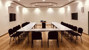 Ein Konferenzraum mit einem langen Tisch, Stühlen und einem Rednerpult.