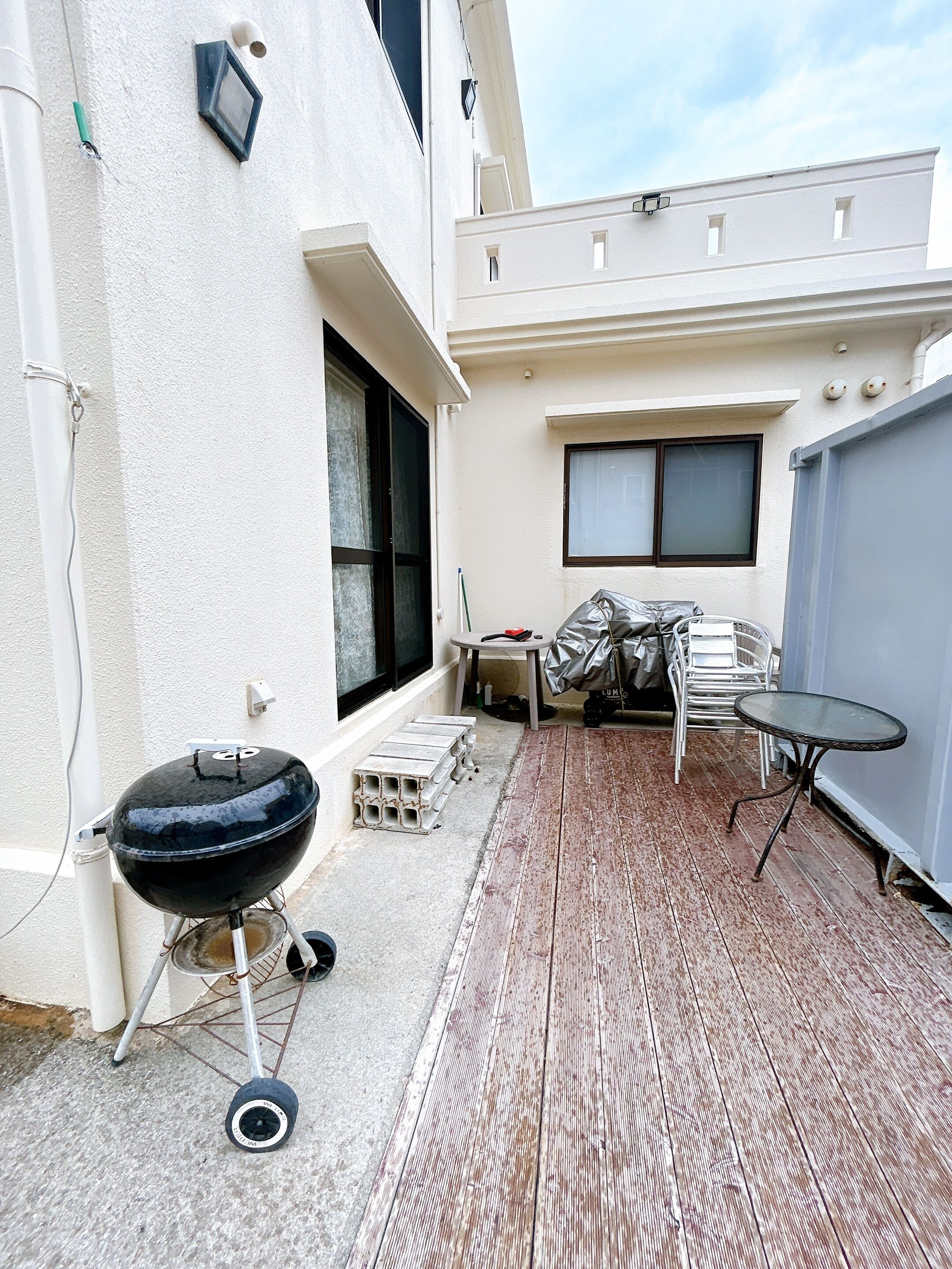 En terrasse med grill, et lille rundt bord og et overdækket siddeområde.