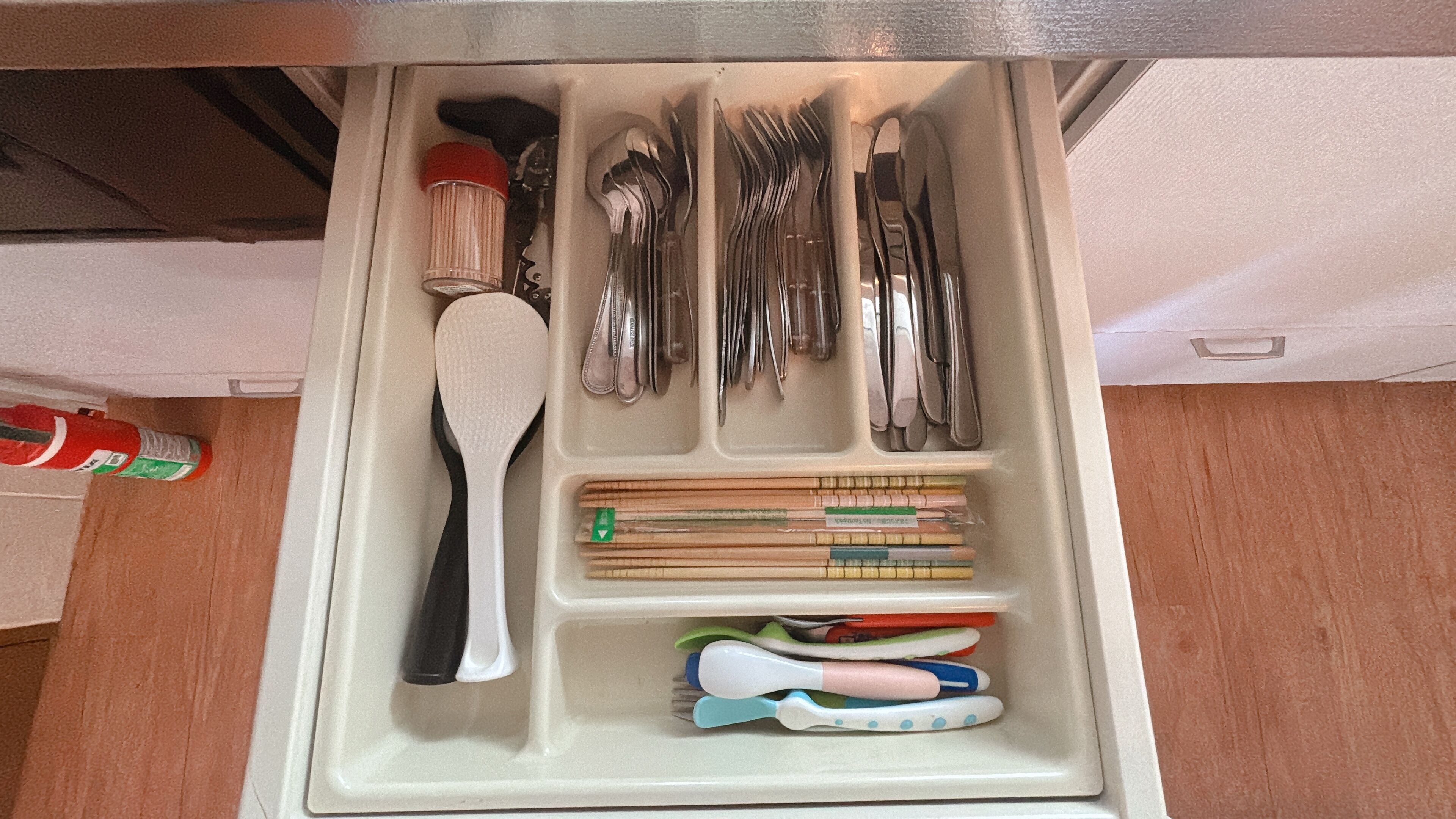 A drawer with utensils, a spatula, and a set of chopsticks.