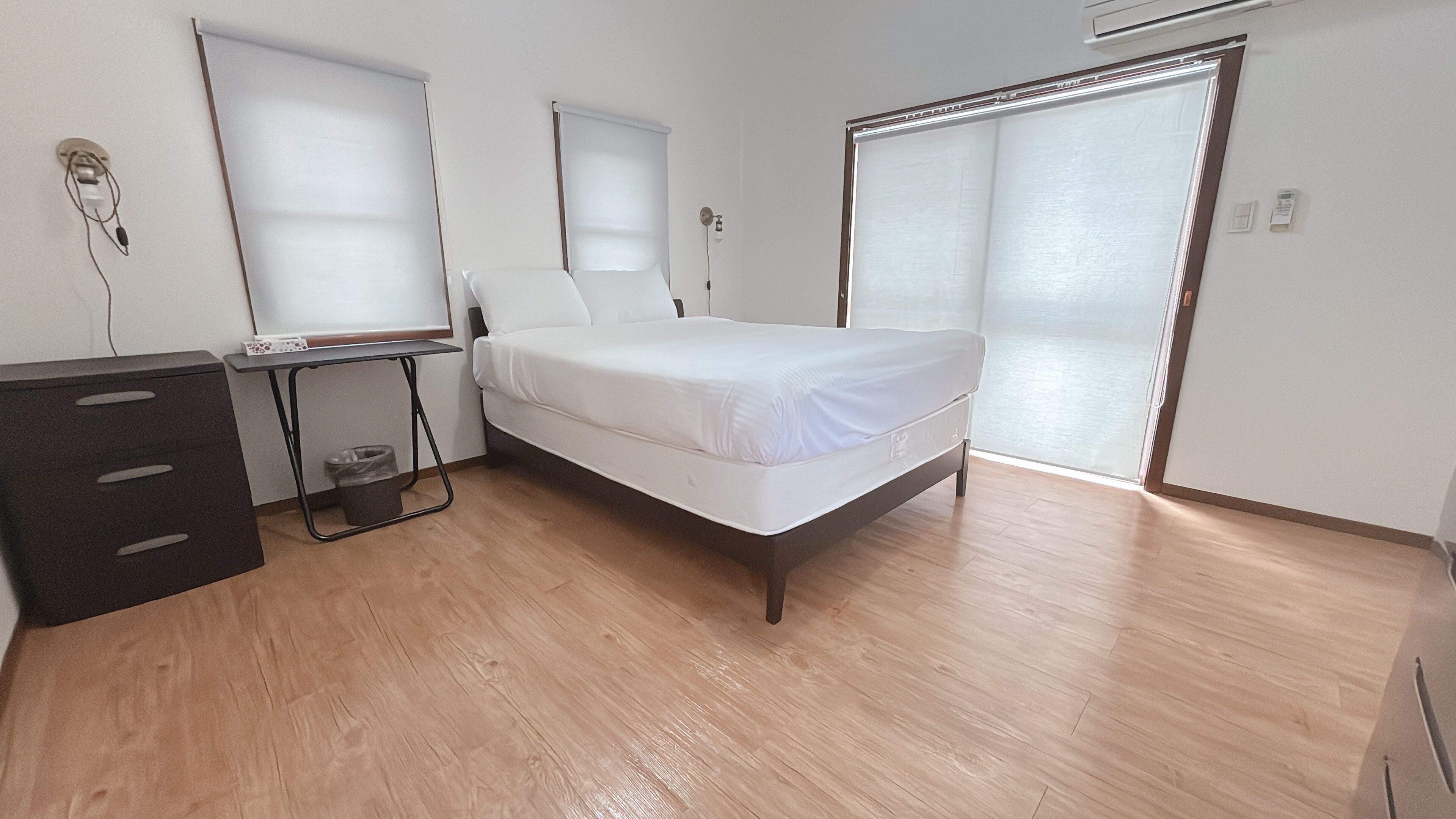 A bedroom with a bed, a desk, and a wardrobe.
