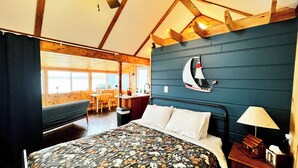 A bedroom with a bed, a desk, and a chair, a small kitchen area, and a view of the outdoors. - Lakefront Cabin w/ Dock & Kayaks, Fishing Escape
Marine Comfort - Cabin 8 (South Haven)
