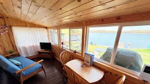 A cabin with a wooden interior, a sofa, a table, chairs, a TV, and a view of a lake. - Lakefront Cabin w/ Dock & Kayaks, Fishing Escape
Marine Comfort - Cabin 8 (South Haven)