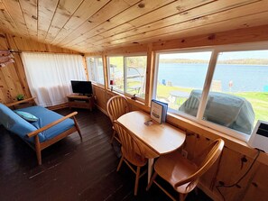 A cabin with a wooden interior, a sofa, a table, chairs, a TV, and a view of a lake. - Lakefront Cabin w/ Dock & Kayaks, Fishing Escape
Marine Comfort - Cabin 8 (South Haven)