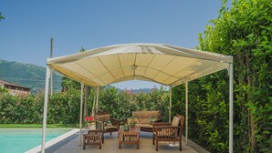 A covered outdoor seating area with a pool in the background. - Gerry House by Interhome (Camaiore)