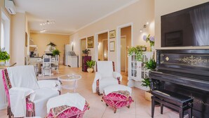 A spacious living room with a piano, white armchairs, and a dining area with a kitchen in the background. - Gerry House by Interhome (Camaiore)