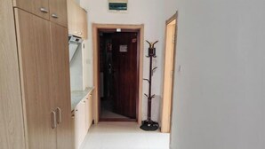 A narrow hallway with wooden cabinets on one side and a coat rack on the other. - Hexigten Banner Yunxuan Hot Spring Homestay (Hexigten Banner)