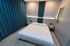 A modern hotel room with a large bed, bedside tables, and a wall-mounted light fixture. - Hexigten Banner Yunxuan Hot Spring Homestay (Hexigten Banner)