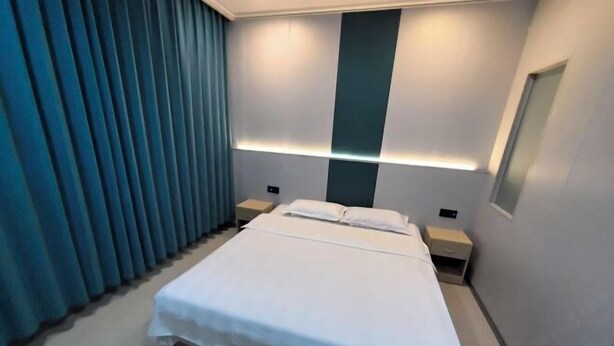 A modern hotel room with a large bed, bedside tables, and a window with curtains. - Hexigten Banner Yunxuan Hot Spring Homestay (Hexigten Banner)