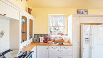 A kitchen with white cabinets, a window, a refrigerator, and various appliances.