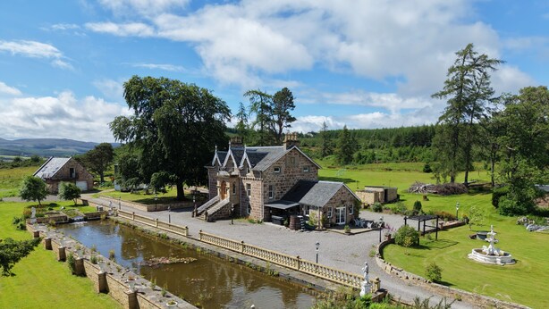 A historic stone building with a large pond, surrounded by well-maintained lawns and trees. - The Doune Luxury Highland House, hot tub, sleeps 12 (Inverness)