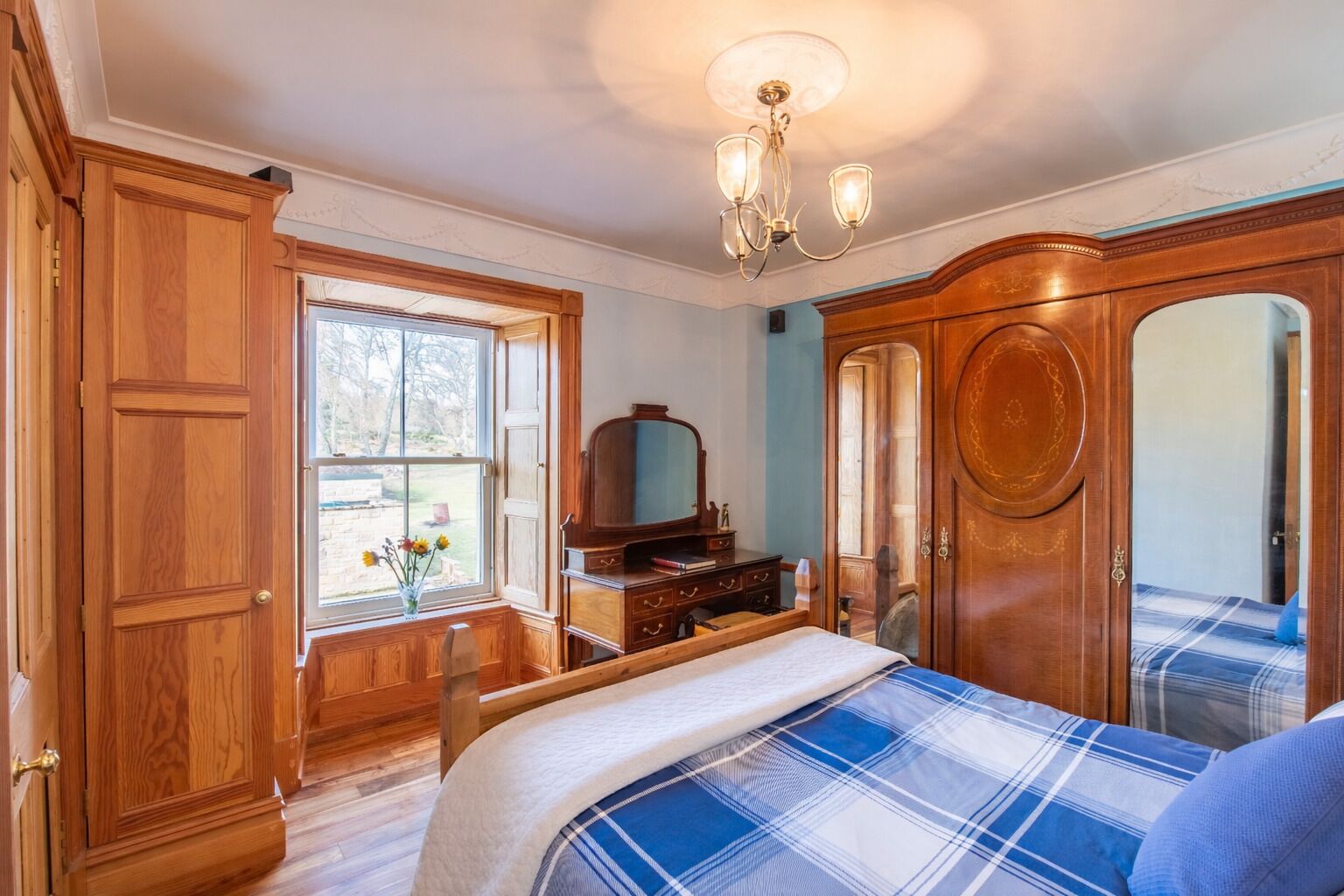 Ein Schlafzimmer mit Bett, Kommode, Spiegel und Kleiderschrank.