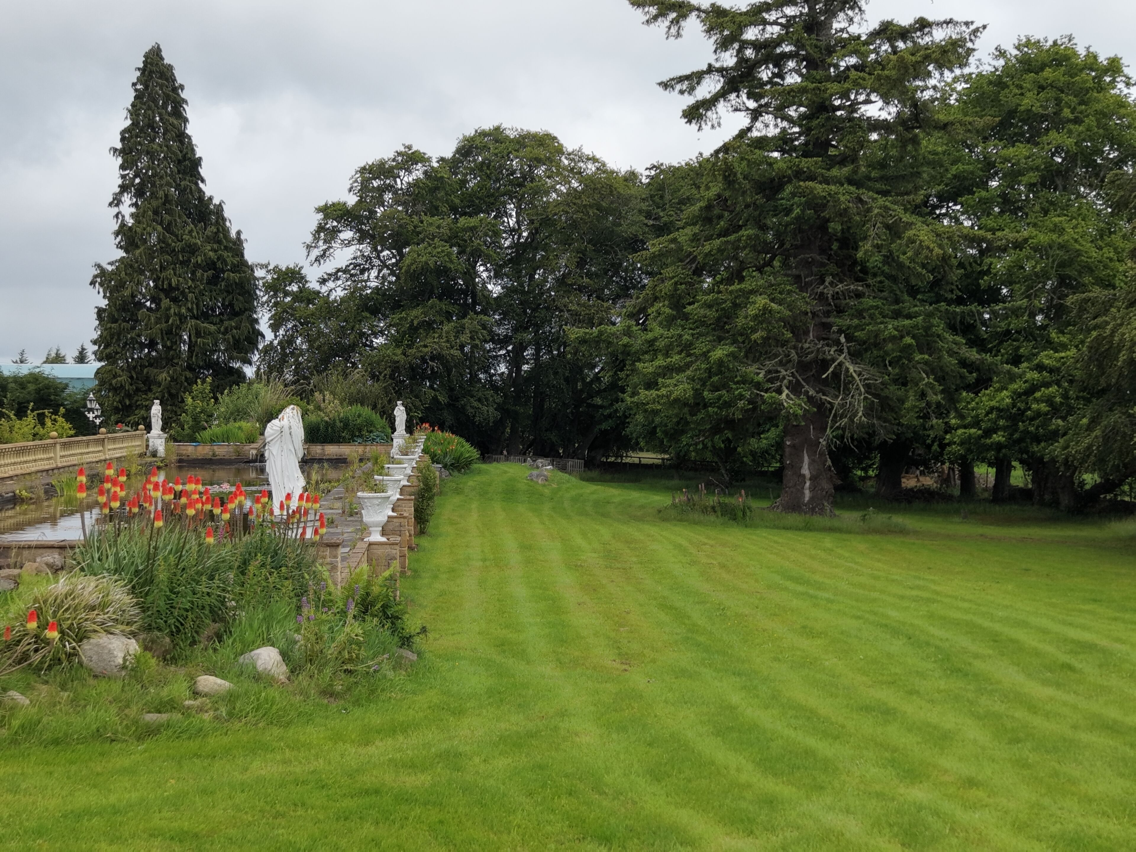 A well-maintained garden with a lawn, stone pathways, and various plants.
