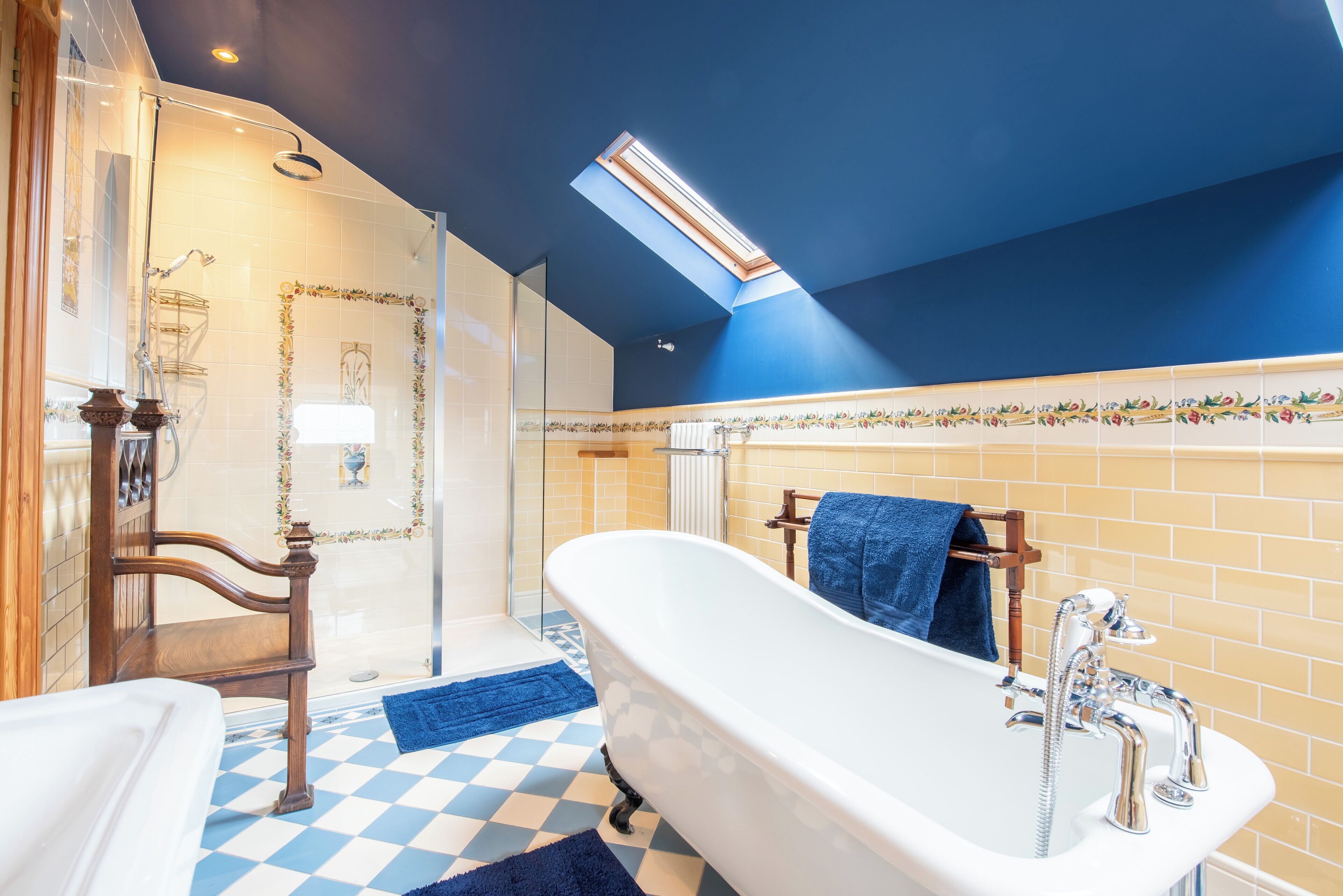 Een badkamer met een vrijstaand bad, een douche en een zwart-witte vloer.