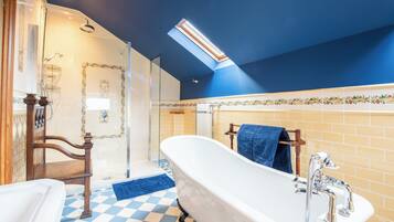 Een badkamer met een vrijstaand bad, een douche en een zwart-witte vloer.