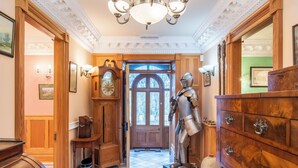 A hallway with a patterned floor, a wooden door, a large clock, and a statue. - The Doune Luxury Highland House, hot tub, sleeps 12 (Inverness)