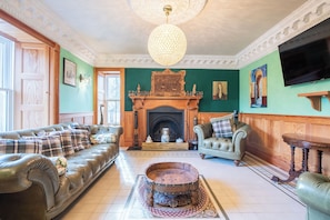 A living room with a fireplace, leather sofas, a wooden coffee table, and a television.