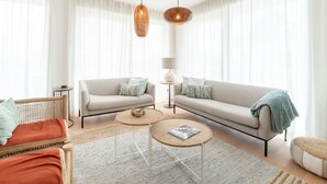 Een moderne woonkamer met twee banken, een salontafel, een lamp en een hanglamp.