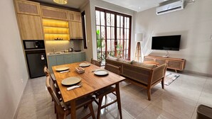 Una cocina moderna con armarios de madera, una mesa de comedor lista para cuatro personas y un ventanal con vistas a zonas verdes.