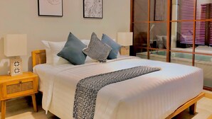 Una cama bien hecha con una colcha estampada, dos lámparas de noche y una mesita de noche de madera.
