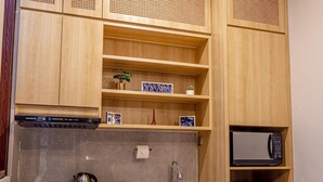 Una cocina con armarios de madera, microondas, cafetera y fregadero.
