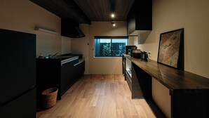 A modern kitchen with wooden flooring, a window, and a view of the outside. - Machiya Villa Gashu (Nagoya)