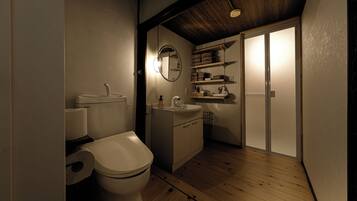 A compact bathroom with a toilet, sink, and shelves for toiletries.