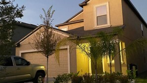 A two-story house with a garage, a driveway, and a well-maintained lawn.