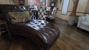 Un sofá de cuero marrón oscuro con diseño capitonado, ubicado en una habitación con piso de madera.