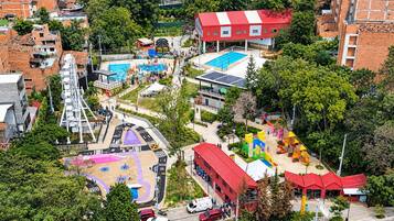 Vue aérienne d’un espace de loisirs comprenant une piscine, une aire de jeux et des installations sportives.