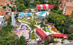 Vista aérea de un área recreativa con piscina, parque infantil e instalaciones deportivas.
