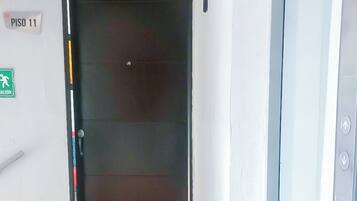 Un pasillo con una puerta cerrada, un letrero que indica 'PISO 11' y una señal de salida de emergencia.