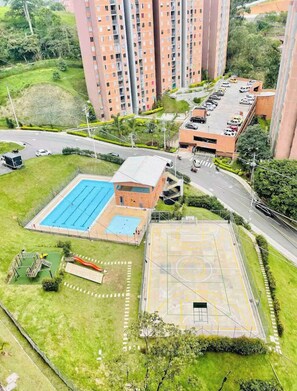 Un quartier résidentiel comprenant des immeubles de grande hauteur, une piscine, un terrain de basketball et un parking.