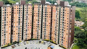 A high-rise residential building with multiple floors, a parking area, and a hilly landscape in the background. - Very natural, Peaceful and Centrally in Medellín (Envigado)