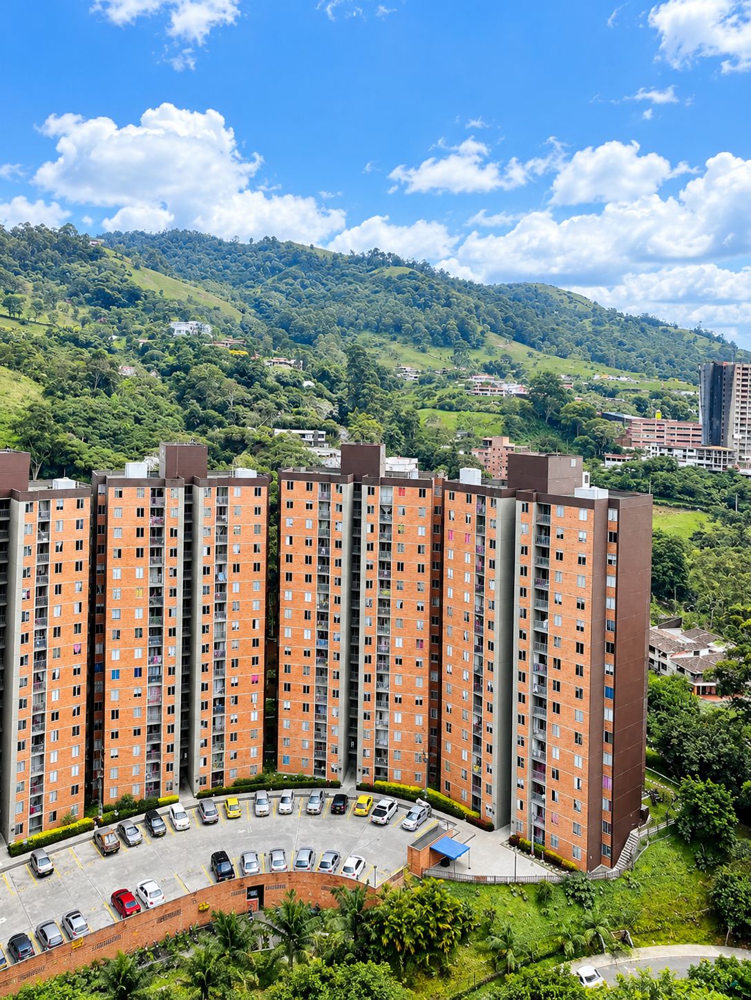 Un immeuble résidentiel de grande hauteur, doté de nombreux étages, d’un parking et surplombant une colline verdoyante.