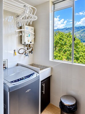Una cocina moderna con lavadora integrada, un tendedero y una ventana con vistas al verdor.